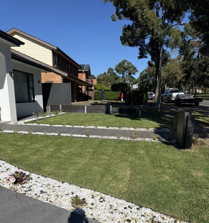 Finished front yard — new lawn edged with white pebble strips and concrete paths